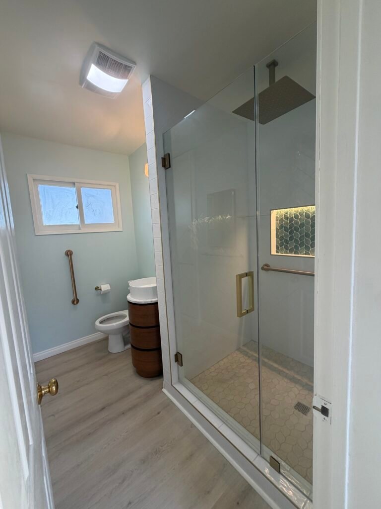 Remodeled bathroom with a tiled shower, glass door, vanity, and grab bars.